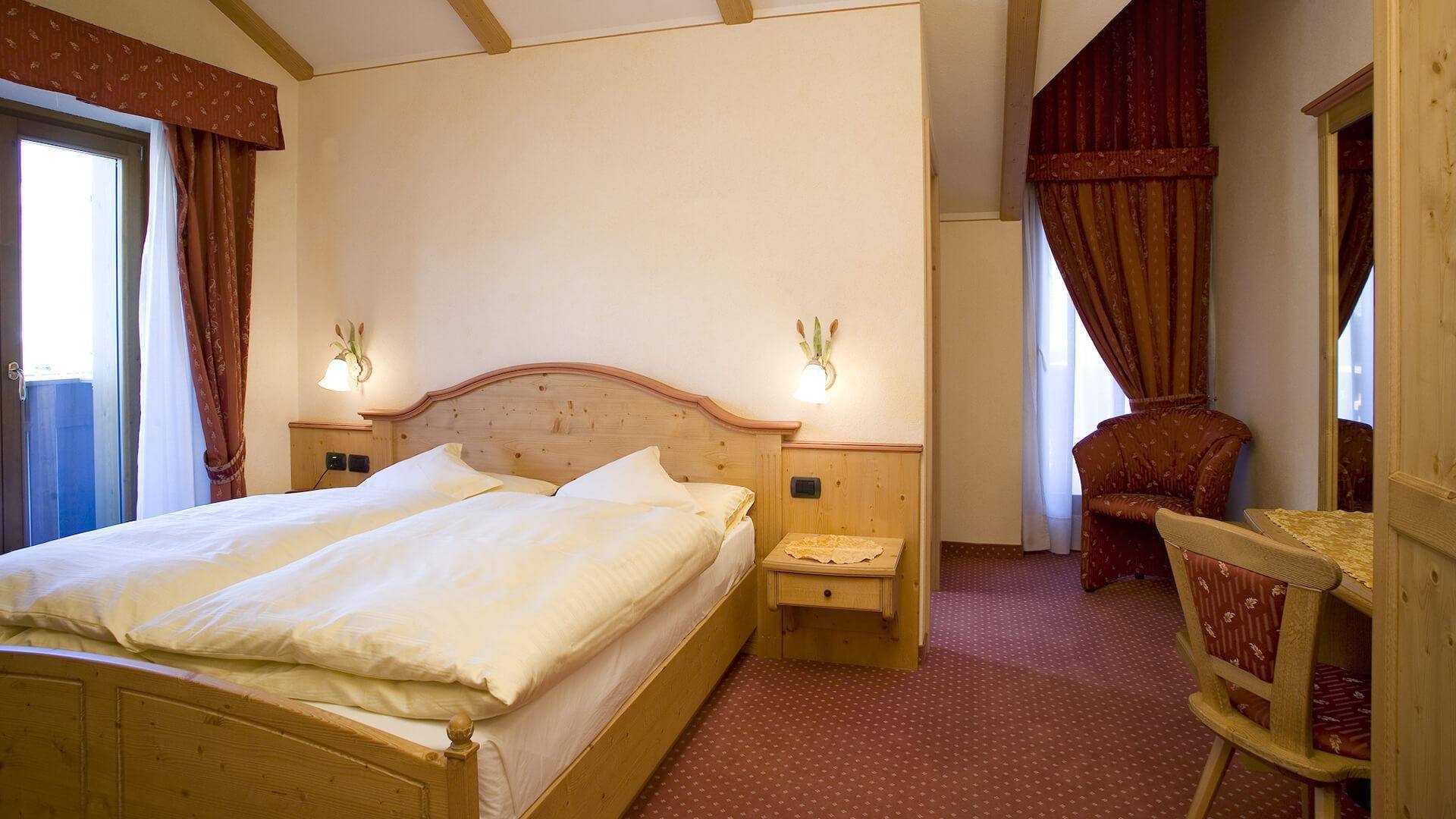 Camera dell’Hotel Cassana con letto a baldacchino e arredi in legno