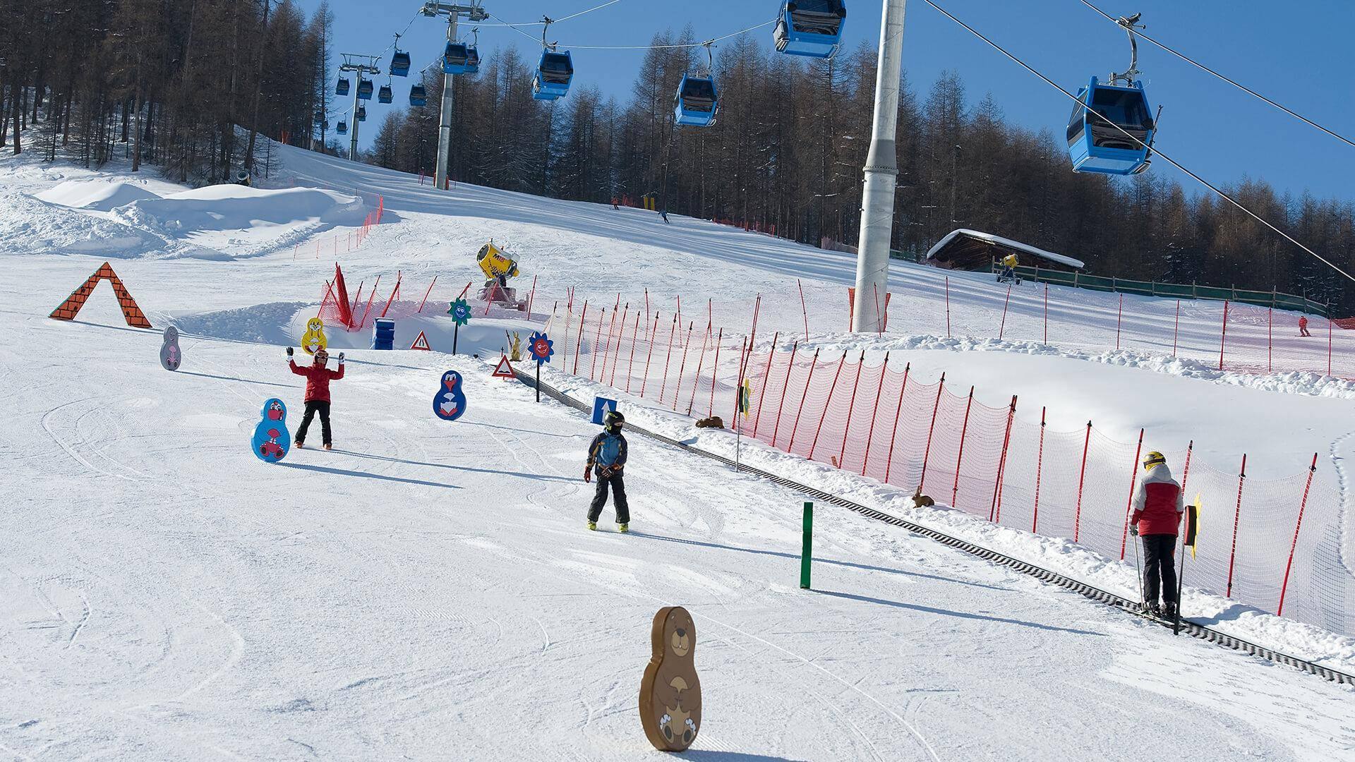 Bambini sulla neve tra le gincane colorate davanti all’hotel