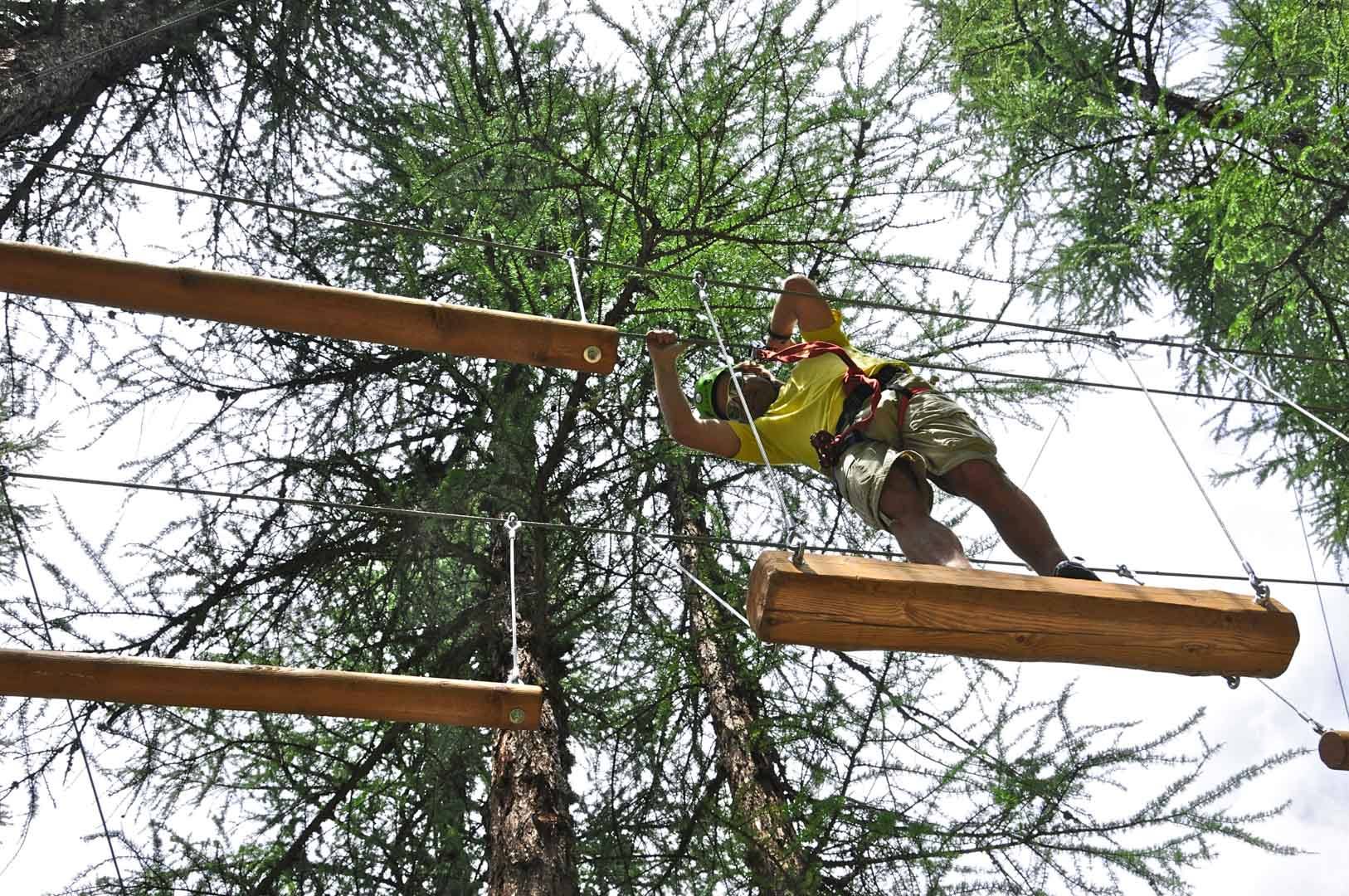 Ragazzo su un percorso sospeso tra i larici del Larix Park
