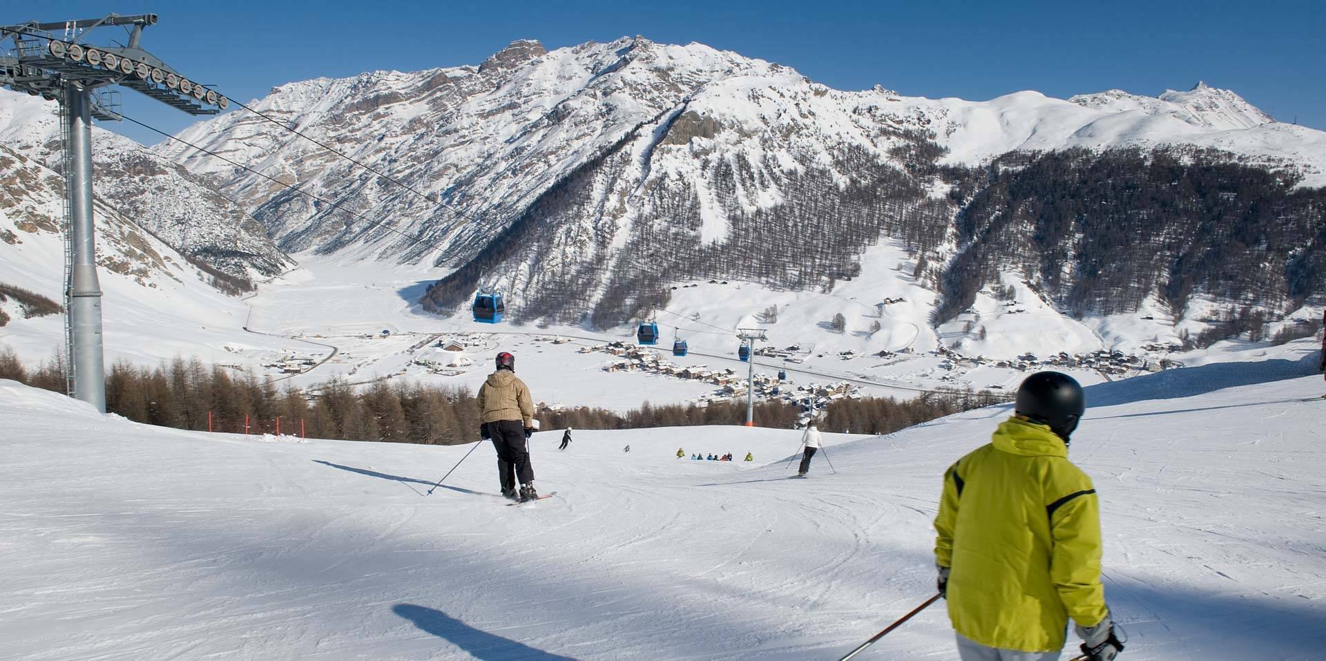 Sciatori sulle piste sopra Livigno con la valle innevata