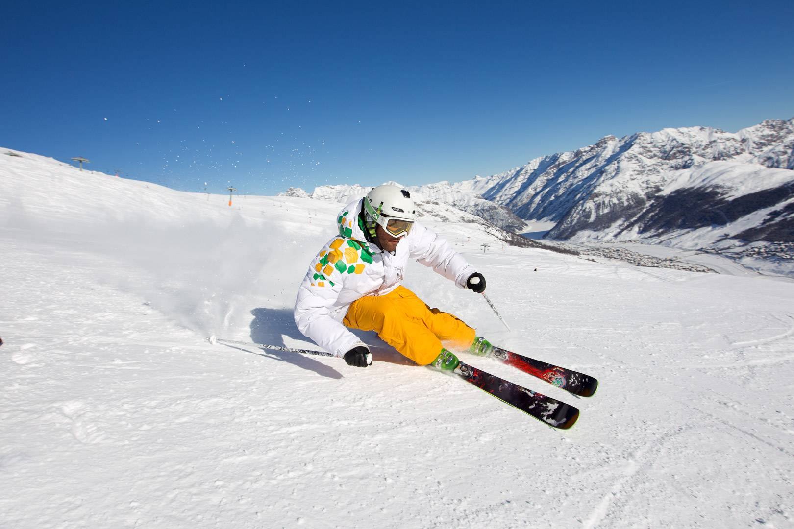Sciatore in curva su una pista di Livigno con il cielo blu